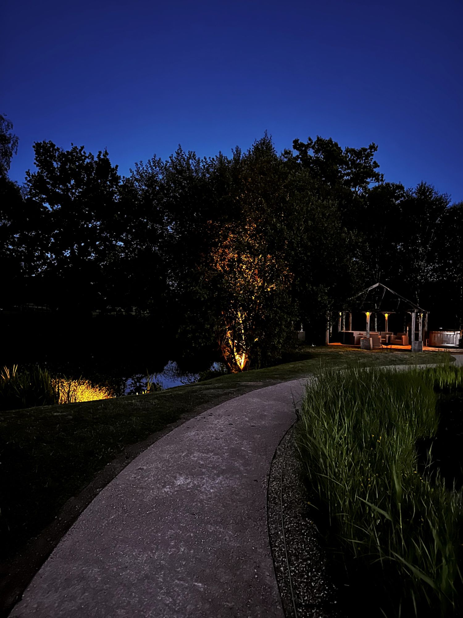 Softly lit garden path leading to a gazebo beside a lake, Hildenborough
