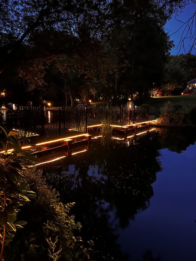 Jetty with linear LED lighting reflected in a lake, Sevenoaks