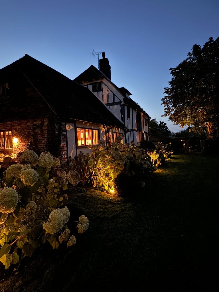 Timber-framed house with uplit hydrangea borders at dusk, Tonbridge